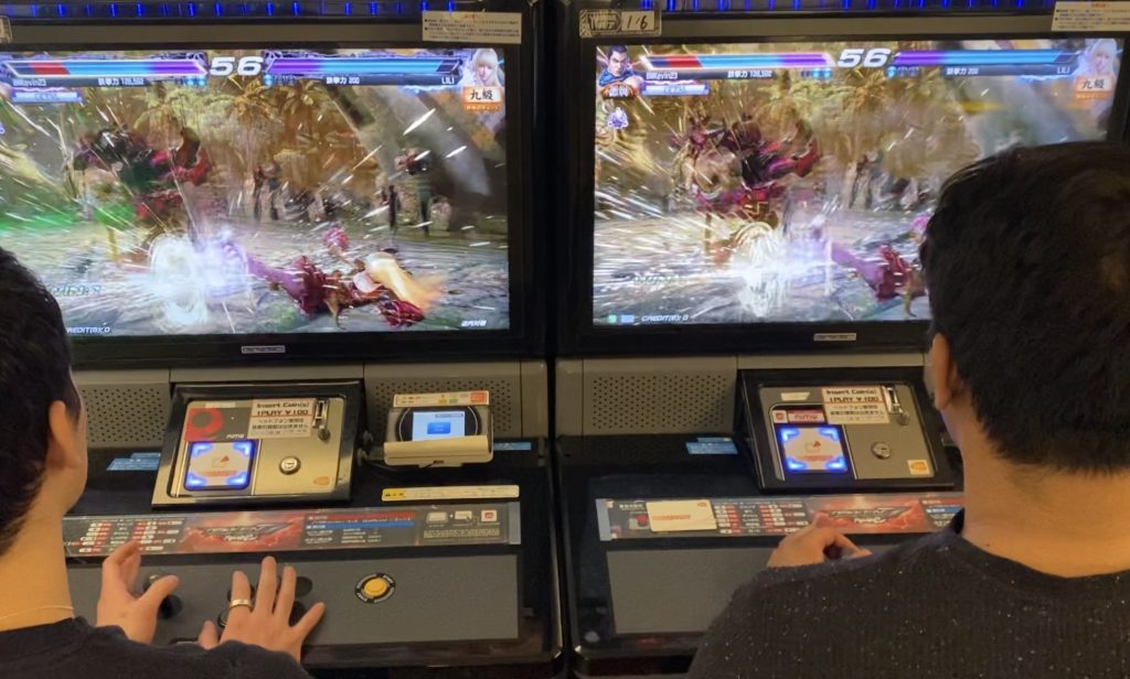 Two men playing an arcade game "Tekken"
