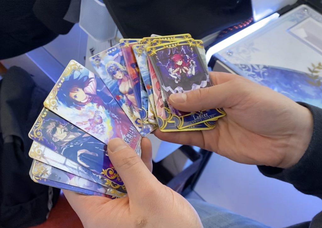 Person holding trading cards of the game Fate Grand Order (FGO)